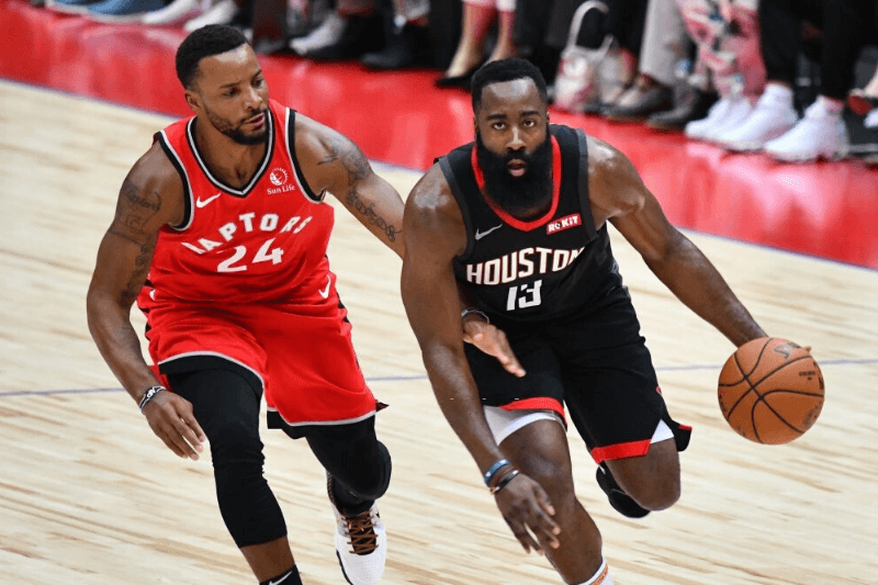 Houston Rockets James Harden (R) dribbles the ball next to Toronto Raptors Norman Powell (L) during their NBA preseason basketball game in Saitama on October 8, 2019.