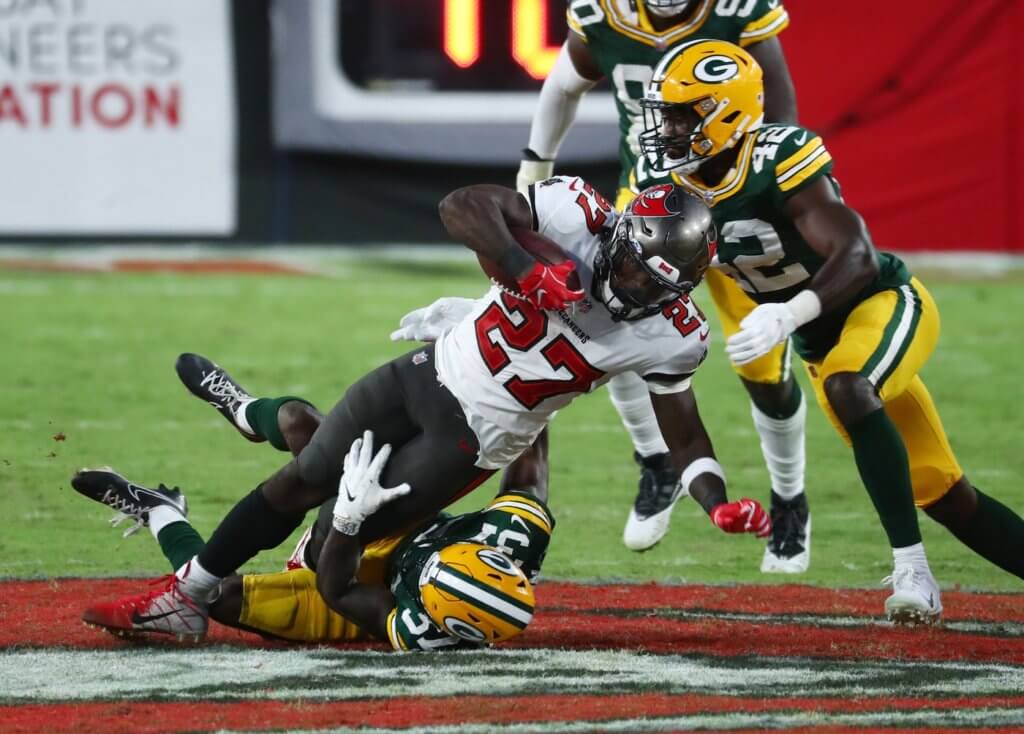 Tampa Bay Buccaneers running back Ronald Jones (27) is tackled by Green Bay Packers cornerback Josh Jackson (37) and inside linebacker Oren Burks (42) during the fourth quarter of a NFL game at Raymond James Stadium.