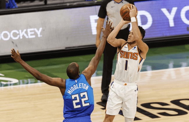 Apr 19, 2021; Milwaukee, Wisconsin, USA; Phoenix Suns guard Devin Booker (1) shoots against Milwaukee Bucks forward Khris Middleton (22) during the third quarter at Fiserv Forum.