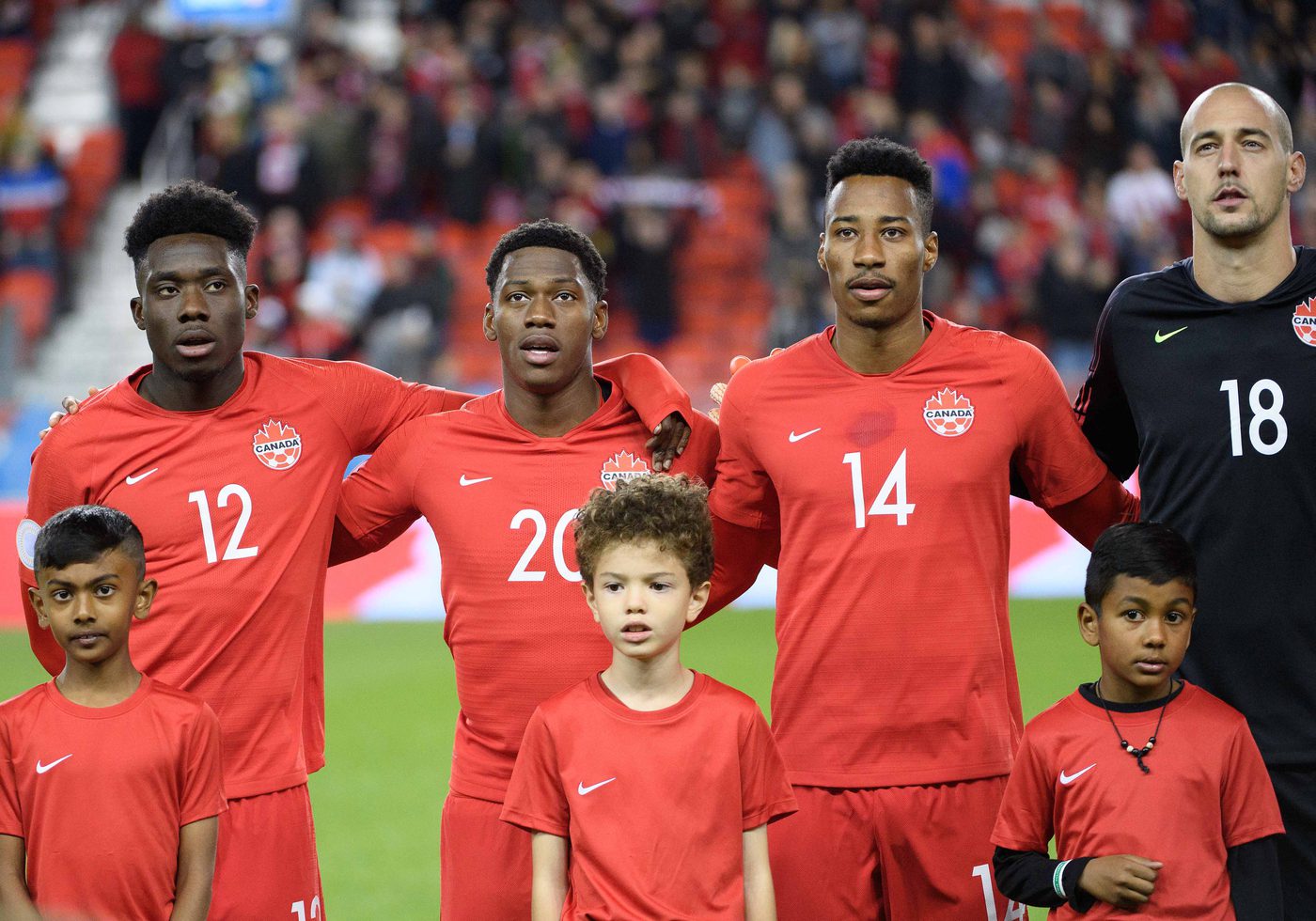 Oct 15, 2019; Toronto, Ontario, CAN; Canada midfielder Alphonso Davies (12) stands with the player escorts during the national anthems before a CONCACAF Nations League soccer match against the USA at BMO Field. Mandatory Credit: Nick Turchiaro-USA TODAY Sports