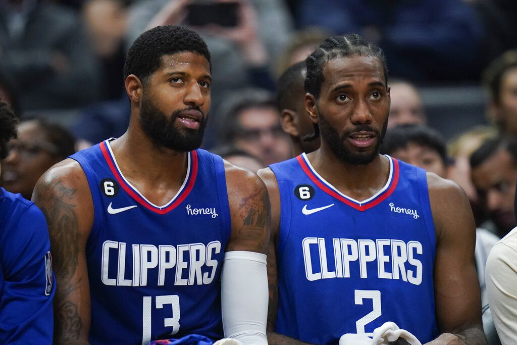 Los Angeles Clippers' Paul George (13) and Kawhi Leonard (2) watch from the bench during the second half of an NBA basketball game against the Boston Celtics Monday, Dec. 12, 2022, in Los Angeles. The Clippers won 113-93. (AP Photo/Jae C. Hong)